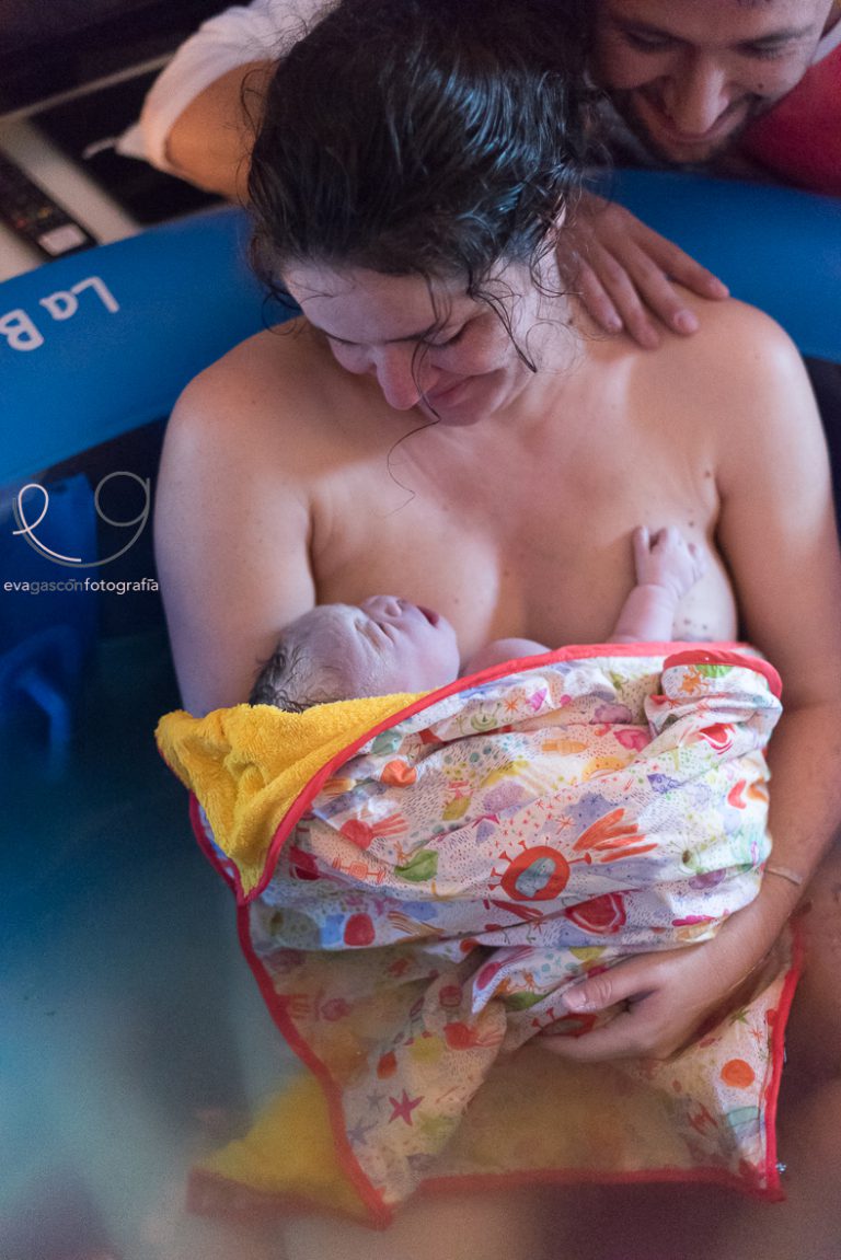 Madre que ha dado a luz en la bañera en un parto en casa mirando a su bebe